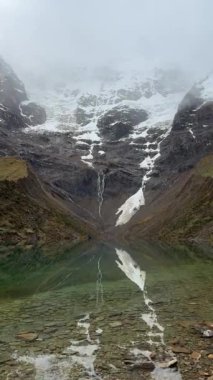 Sisli atmosfer ve mükemmel yansıma bu nefes kesici dağ manzarasında bir huzur ve korku hissi yaratıyor. Yüksek kalite 4k görüntü.