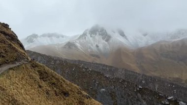 Sisli bir dağ yolu, engebeli yamaçların bulutlarla buluştuğu Abra Salkantay 'ın karla kaplı tepelerine doğru esiyor. Yüksek kalite 4k görüntü.
