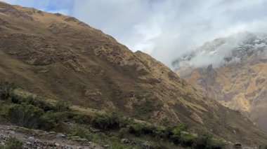 Yüksek And Dağları 'nın dramatik manzarası, Peru' daki Nevado Humantay 'ın heybetli, karla kaplı yamaçlarına uzanan altın tepeleri gözler önüne seriyor. Yüksek kalite 4k görüntü.