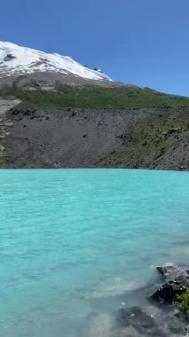 Huemul Buzulu 'nun altındaki canlı turkuaz Laguna Huemul' un panoramik görüntüsü. Patagonya 'da engebeli kayalık yamaçlar, yeşil ormanlar ve açık mavi gökyüzünün altındaki karlı zirveler. Yüksek kalite 4k görüntü