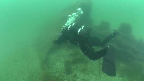 Technische duiker zwemt over fragment van het wrak. — Stockvideo