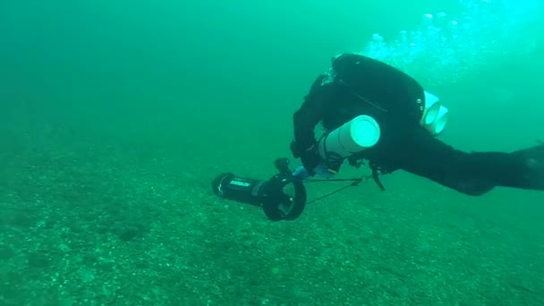 De duiker verwijderd langzaam op een onderwater scooter. — Stockvideo
