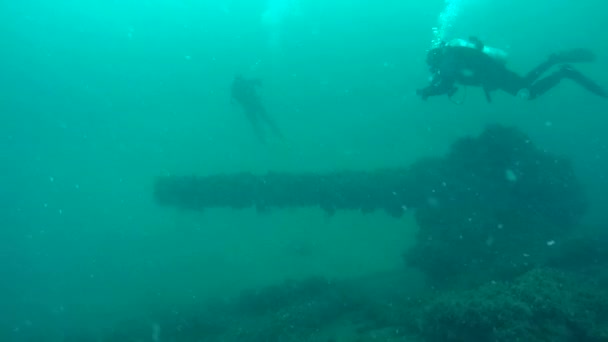 Zwei Taucher schwimmen über der Kanone des gesunkenen Kriegsschiffs. — Stockvideo