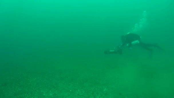 Een duiker zwemt boven de bodem de onderwater scooter rijden. — Stockvideo