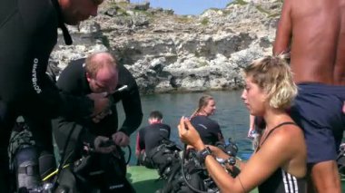 Dalış merkezinin eğitmeni dalış ekipmanlarının katılımcılarına yardımcı olur.