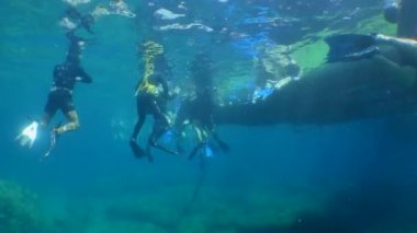 Dalış eğitimi: yüzen platformun kenarında bir grup öğrenci dalgıç, alt görünüm.