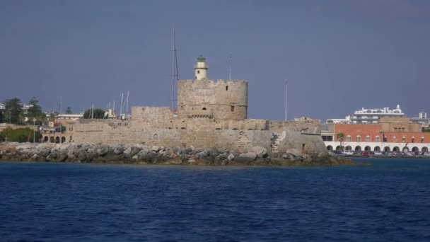 Ősi torony védi a kikötő bejáratát, kilátás egy mozgó hajóról. Rodosz, Görögország. — Stock videók