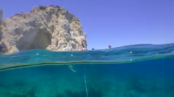 Touristengruppe auf SUP-Boards vor der Kulisse der Küsten-Klippen, Kamera halb unter Wasser. — Stockvideo