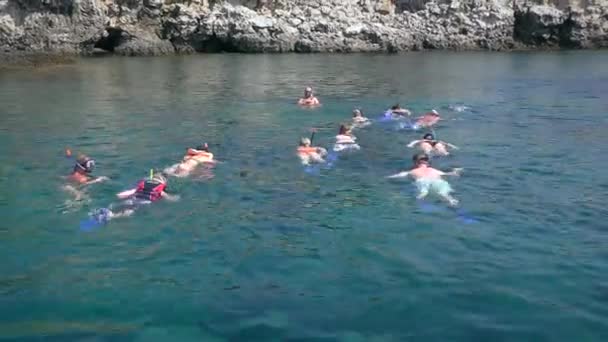 Snorkel: un grupo de turistas en máscaras submarinas contra una costa rocosa. — Vídeo de stock