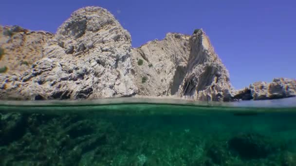Split, a kamera a tenger szintjén egyszerre mutatja a víz alatti és felszíni sziklás tengerparti táj. — Stock videók
