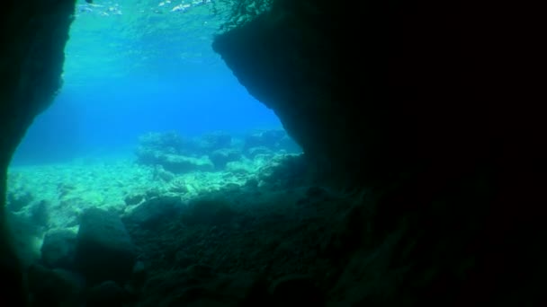 Kamera vychází z temného podmořského kamenného tunelu do otevřené vody. — Stock video