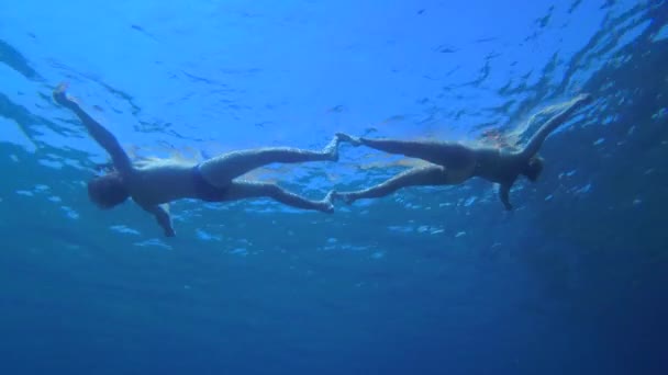 Un homme et une femme gisent à la surface de l'eau formant une figure commune, une vue du bas. — Video