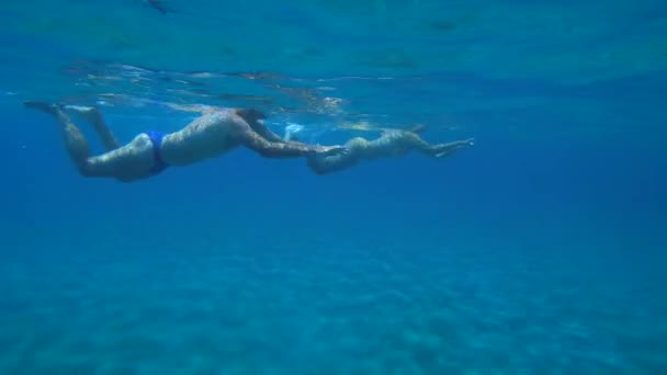 Jeune homme et femme nagent au-dessus de l'eau peu profonde de sable de mer, vue du bas. — Video