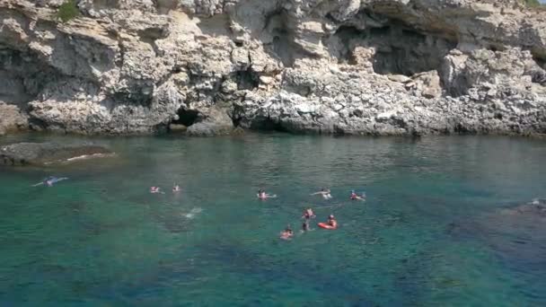 Šnorchlování: skupina turistů v podmořských maskách proti skalnatému břehu. — Stock video