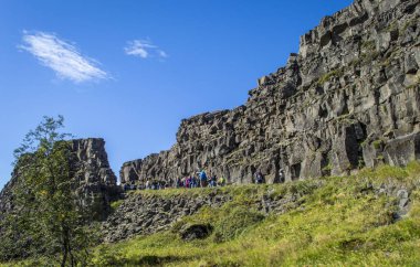 Selfoss, İzlanda, 28 Ağustos 2025. Güneşli bir günde İzlanda 'daki Thingvellir Ulusal Parkı' ndaki dramatik kayalık vadide yürüyen bir grup turist.