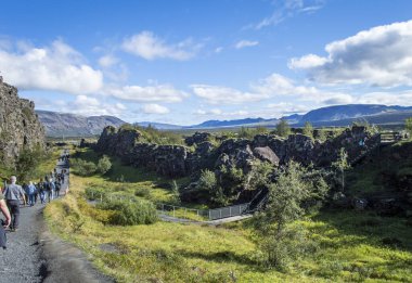 Selfoss, İzlanda, 28 Ağustos 2025. Güneşli bir günde İzlanda 'daki Thingvellir Ulusal Parkı' ndaki dramatik kayalık vadide yürüyen bir grup turist.