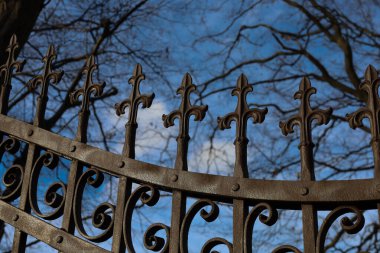 Bu çekim, derin mavi gökyüzüne karşı dekoratif çapraz şekilli dekoratif çitlerle işlenmiş demir kapı veya çitin üst kısmının yakın çekimini içerir..