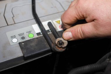 Yakından çekilen bir el, metal bir diş telinin fındığını sıkıyor. Bu da arabanın aküsünü kompartımanına bağlıyor. Kurulum sürecini gösteriyor..