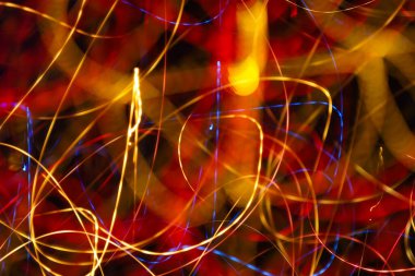 Soyut ışık çizimi karmaşık altın, kırmızı ve mavi ışık yollarından oluşan dinamik bir desen yaratır. Uzun pozlama fotoğrafçılığı, parlak gece ışıklarını tasarım ve kapak sanatı için mükemmel enerjik, geleceksel bir arka plana dönüştürür..