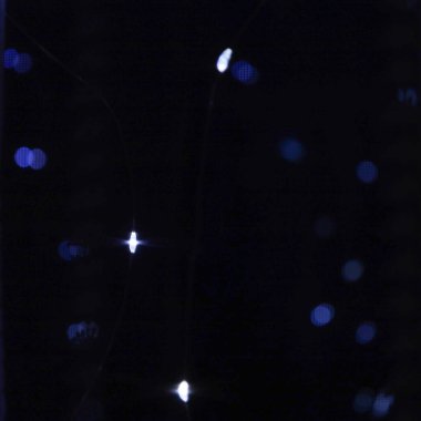 Parlak beyaz LED çelenk ışıkları karanlık bir arka planda parlıyor, büyülü ve gececi bir barış ortamı yaratıyor..