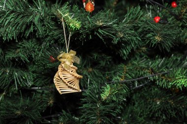 Geleneksel bir el yapımı saman Noel süslemesi altın yaylı spiral çan şeklinde yeşil yapay çam iğnelerine asılı..