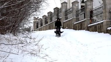Neşeli erkek ve kız kardeşler, ahşap kızaklarla karlı bir tepeden hızla kayarak kış gününün tadını çıkarıyorlar. Çocuklar, soğuk mevsimde kabarık beyaz karlar arasında aktif olarak eğlenmenin verdiği gerçek keyfi hissederek yürekten gülüyorlar..