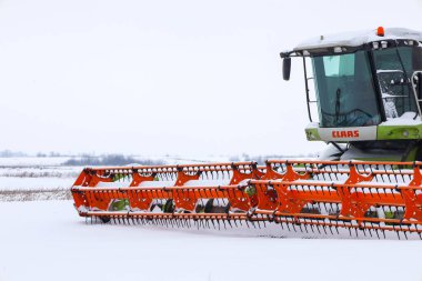 Lviv, Ukrayna - 07 Ocak 2026: Büyük bir Claas 'ın parlak turuncu başlığı, koyu beyaz kar arkaplanına yakın plan çekimde öne çıkıyor.