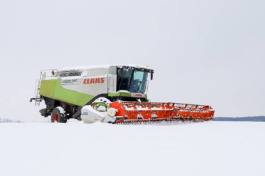 Lviv, Ukrayna - 07 Ocak 2026: Bir Claas Lexion 580 biçerdöveri büyük turuncu bir başlıkla birleştirerek yoğun bir alanın ortasında duruyor..