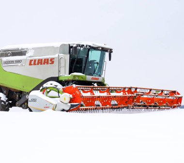 Lviv, Ukrayna - 07 Ocak 2026: Bir Claas Lexion 580 'in güçlü taksisi ve parlak turuncu başlığı derin beyaz kar ortasında yakın plan çekimde yakalanır..
