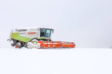 Lviv, Ukrayna - 07 Ocak 2026: Büyük tarım makinesi, sezon dışında sonsuz kış ufkuna ve parlak bulutlu gökyüzüne karşı muazzam görünüyor.