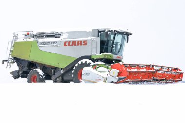 Lviv, Ukrayna - 7 Ocak 2026: Modern bir Claas Lexion 580 biçerdöveri kış ayazları sırasında geniş beyaz bir tarlanın ortasında duruyor.