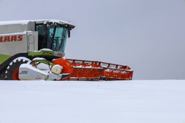 Lviv, Ukrayna - 07 Ocak 2026: Parlak turuncu detaylara sahip bu güçlü makine, çiftçilik faaliyetlerinin mevsimsel durmasını gözler önüne seren minimalist bir kış manzarasına karşı çıkıyor.