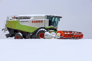 Lviv, Ukrayna - 07 Ocak 2026: Güçlü bir Claas Lexion 580 hasat makinası el değmemiş bir kış tarlasının ortasında karla kaplı duruyor.
