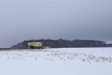 Lviv, Ukrayna - 7 Ocak 2026: Modern bir Claas Lexion hasat makinası, hasat sezonunun sonlarına doğru karla kaplı geniş bir alanda çalışır..