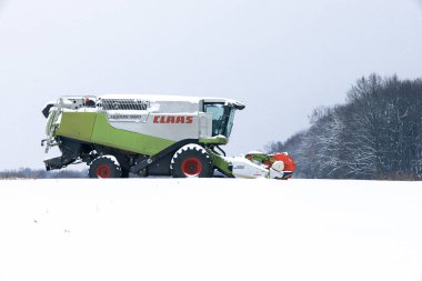 Lviv, Ukrayna - 07 Ocak 2026: Güçlü bir Claas Lexion 580 biçerdöveri karla kaplı geniş bir alanın ortasında duruyor ve sert kış koşullarında çalışmaya hazır olduğunu gösteriyor.