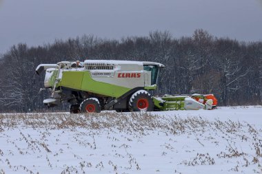 Lviv, Ukrayna - 07 Ocak 2026: Güçlü bir Claas Lexion 580 hasat mevsimi boyunca karla kaplı bir tarlada duruyor.