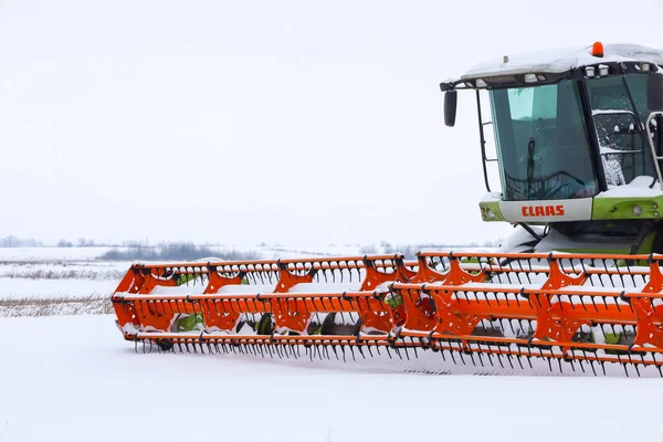 Lviv, Ukrayna - 07 Ocak 2026: Büyük bir Claas 'ın parlak turuncu başlığı, koyu beyaz kar arkaplanına yakın plan çekimde öne çıkıyor.