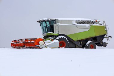Yakın plandaki güçlü ve modern bir hasat makinesi aşırı kış hasadı sırasında derin karı yener. Modern tarım makineleri temiz beyaz bir ufuk üzerinde çalışır.,