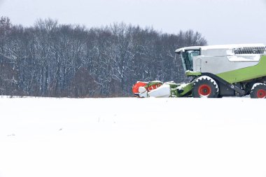 Güçlü, modern bir hasat makinası karlı bir arazide kışın aşırı hasat sırasında çalışır..