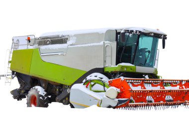 Modern hasat makineleri taze kar tabakasıyla kaplıdır, çarpıcı bir kontrast yaratır ve tarım sezonunun sonunu sembolize eder..