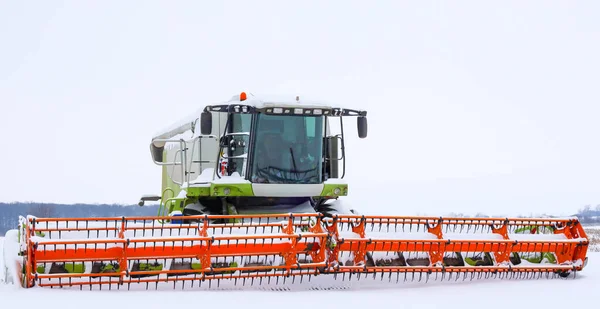 Parlak turuncu başlıklı bir biçerdöver kış ayazları sırasında karlı bir tarlanın ortasında durur. Tarım makinesi tamamen kar ve kar ile kaplı. Bu da şiddetli hava koşulları nedeniyle tarla çalışmalarının durdurulduğunu gösteriyor..