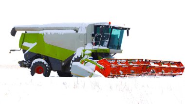 Kış tatilinde karlı bir arazide profil görüntüsü olan güçlü bir modern hasat makinesi. Parlak turuncu başlıklı büyük beyaz ve yeşil makine, çarpıcı bir endüstriyel görüntü oluşturan taze kar tabakasıyla kaplıdır. .