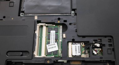 Parçalanmış bir dizüstü bilgisayarın dahili mimarisi, yüklü RAM modüllerini ve teknik yuvalarda kablosuz iletişim kartını gösterir..