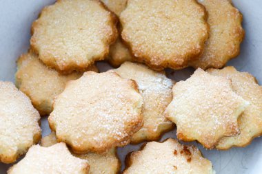 Kenarları deniz tarağı kaplı ev yapımı kurabiye, bol bol şeker serpiştirilmiş, hafif bir kabın içinde dinleniyor..