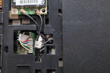 Wi-Fi modül antenleri ve güç kurdele kablolarını gösteren parçalanmış bir dizüstü bilgisayarın iç bileşenleri. Aygıt bakımı sırasında ana karttaki bağlantı ve kabloların ayrıntılı görünümü.