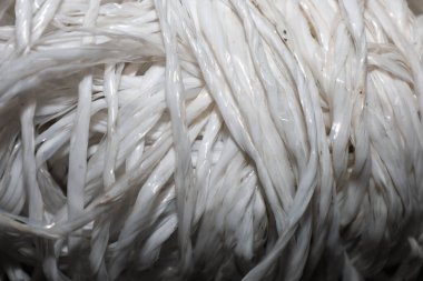 Beyaz polipropilen ip rulosunun makro görüntüsü sentetik liflerin parlak dokusunu gösteriyor. Bu dayanıklı sicim yoğun örgülü bir yapıya ve profesyonel bir sona sahip. Bu da onu endüstriyel ambalaj ve nakliye için mükemmel kılıyor.,