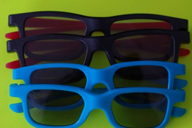 Kırmızı şakaklı bir çift klasik siyah 3D gözlük zengin bir kırmızı zemin üzerine yerleştirilir. Derin renk düzeni ve nesnelerin paralel düzeni modern bir sinemanın atmosferini mükemmel bir şekilde aktaran ve paylaşan şık bir kompozisyon oluşturur. .