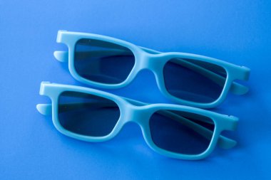 İki çift yumuşak mavi 3D gözlük zengin mavi bir zemin üzerinde üst üste yerleştirilir ve uyumlu bir tek renkli kompozisyon oluşturur..