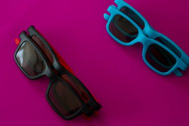 İki çift katlanmış plastik gözlük içeren zengin bir kompozisyon turkuaz mavi ve siyah, canlı mor (morumsu) bir arka planda kırmızı tapınak..