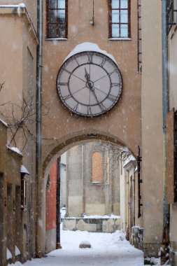 Lviv, Ukrayna - 24 Ocak 2026: Yoğun bir kar yağışı sırasında Roma rakamlarıyla kaplı büyük bir açık hava saati antik bir kemeri süslüyor.